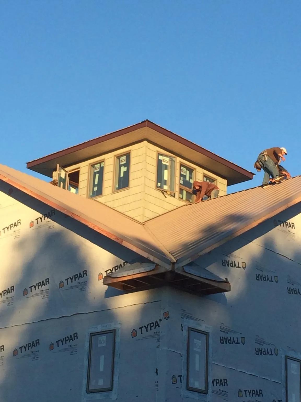 Roofers working around a rooftop cupola on a new metal roof at sunset — Roof Waterproofing in Liberty Center by Roofing Brothers